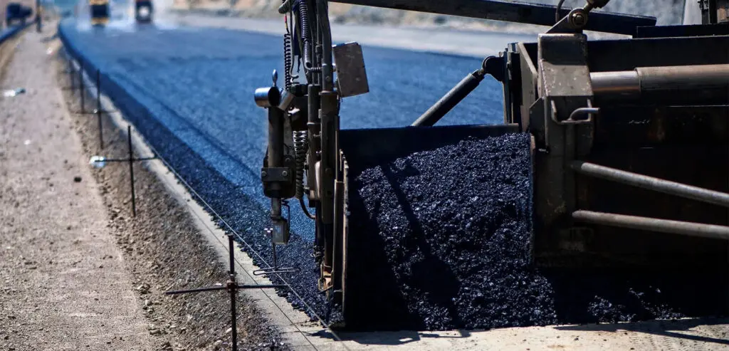 A machine is laying on the ground near some blue gravel.