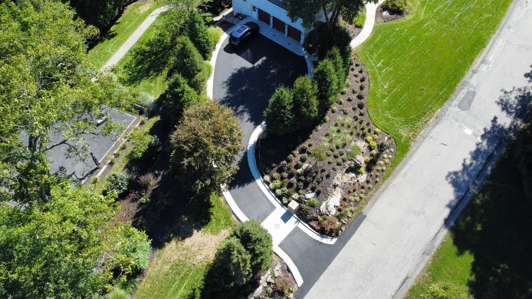 A bird 's eye view of a driveway and landscaping.
