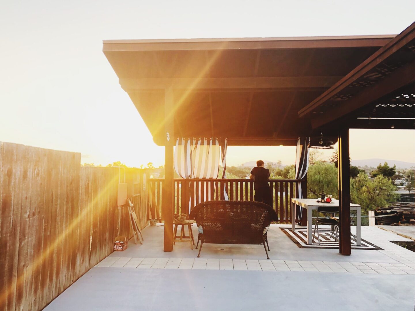 Person leaning on patio railing at sunset