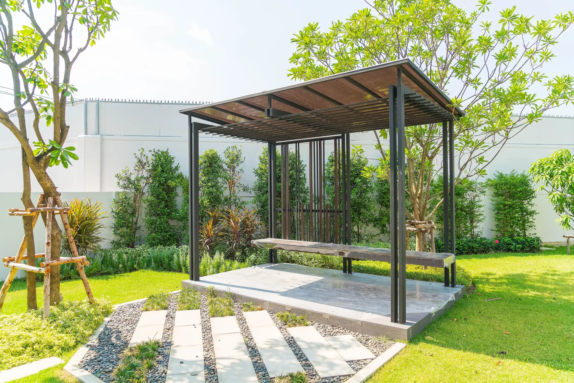Wooden pergola with bench in green garden