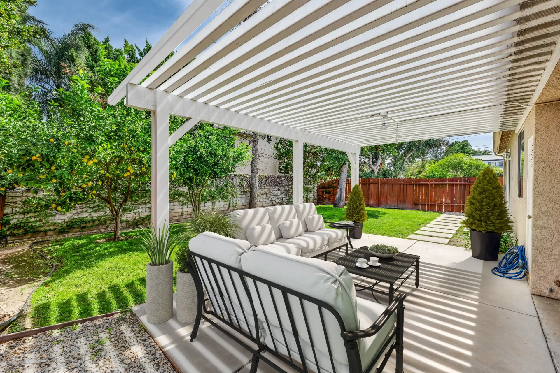 Backyard patio with white pergola and sofa